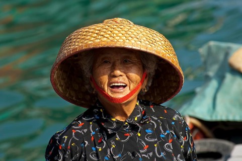 Laughing old Chinese fishmonger with straw hat