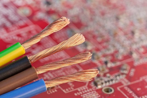 Copper wires in front of a red circuit board