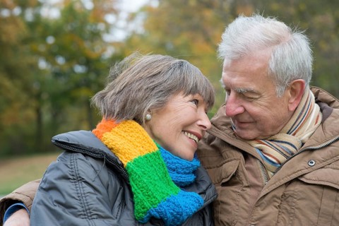 Senior couple sitting arm in arm on a park bench