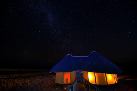 Illuminated chalet or cabin of the Sossus Dune Lodge at night