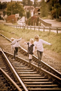 Three children walking on railway lines