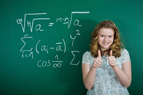Schoolgirl standing in front of a school blackboard with mathematical formulas