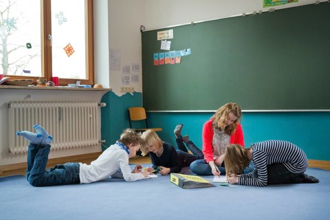 Students at an independant school sitting and lying to work on the ground