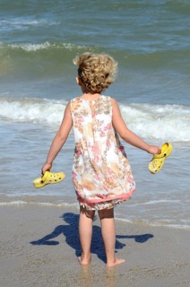 Kleines Madchen am Strand sieht auf die Wellen