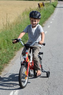 Boy riding a bicycle with training wheels