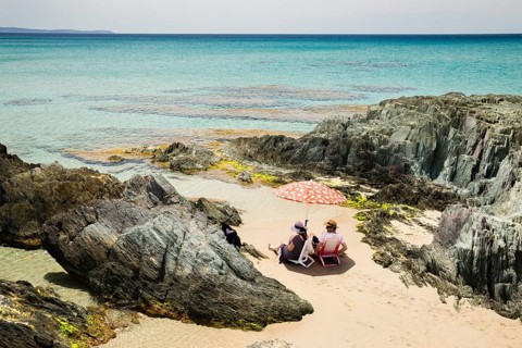 Couple sitting on the beach of Masua