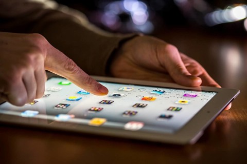 Finger touching the touch screen of an Apple iPad