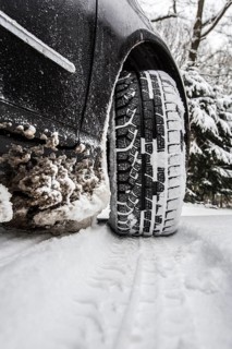 Car with winter tyres parked on a road covered with snow