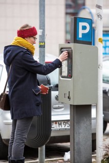 Woman purchasing a parking ticket from a parking ticket vending machine