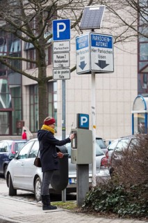 Woman purchasing a parking ticket from a solar powered parking ticket vending machine