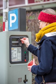 Woman purchasing a parking ticket from a parking ticket vending machine
