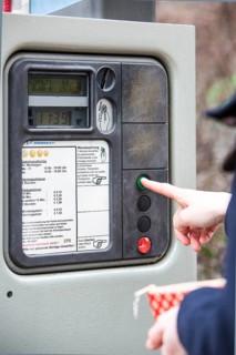 Woman purchasing a parking ticket from a parking ticket vending machine