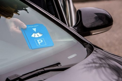 Woman putting a parking disc with her arrival time behind the windscreen