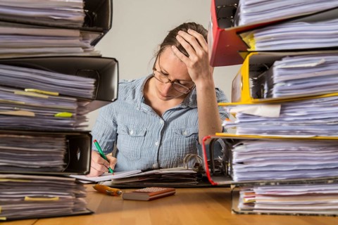 Woman working at a desk between stacks of files