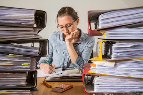 Woman working at a desk between stacks of files