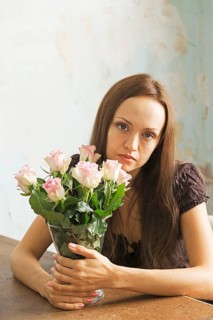 Young woman sitting at a table with flowers in a vase