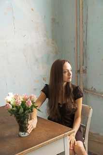 Young woman sitting at a table with flowers in a vase