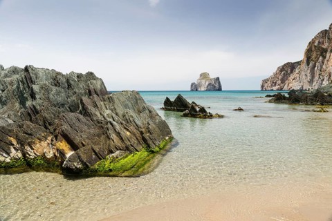 Spiaggia di Masua bay with the Pan di Zuccherof rock island in the sea