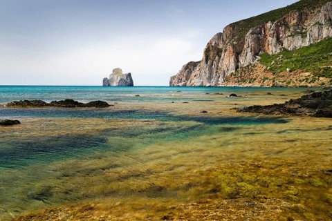 Spiaggia di Masua bay with the Pan di Zuccherof rock island in the sea
