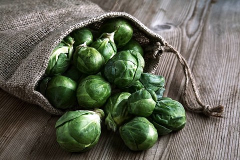 Organic Brussels sprouts in a jute sack on a wooden surface
