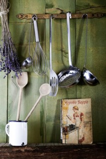 Old cookbook with cooking utensils in front of a green wooden wall