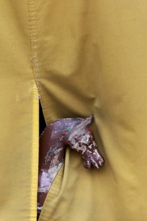 Old carousel horse looking out underneath a tarpaulin
