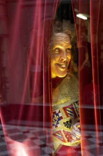 Wax figure looking through a gap in the curtain