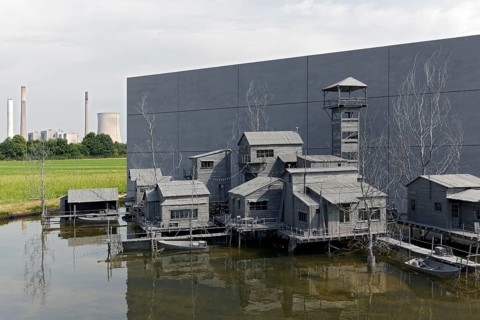 Village on stilts in front of an industrial scene