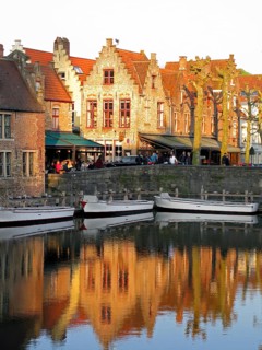 Guild houses with stepped gables being reflected in a canal with boats