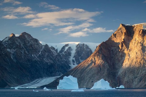 Icebergs in front of the mountain and glacier scenery in Vest Frederiksdal in the morning light
