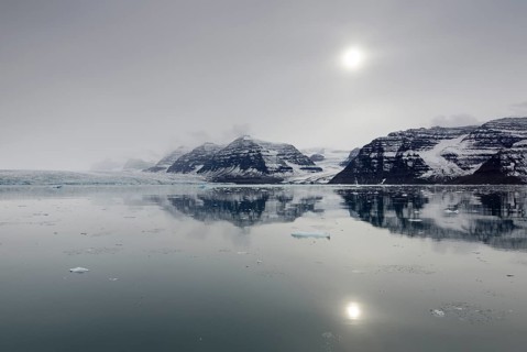 Perfect reflection of mountains and glacial scenery in the pale sunshine of an overcast stormy day