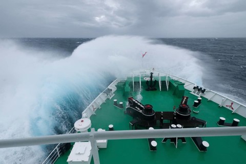 A huge wave is breaking over the bow of the expedition cruise ship MS Expedition in the Drake Passage