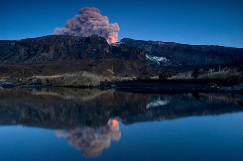 Eruption of Eyjafjallajoekull volcano with its reflection