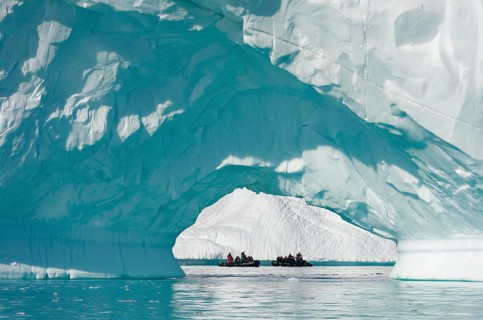 Zodiac inflatable boats seen through the arch of a large iceberg