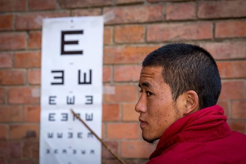 A monk from Amitabha Monastery carrying out a vision test for poor villagers