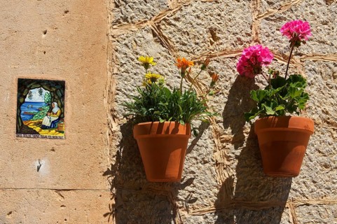 Holy image and a flower pots on a house wall