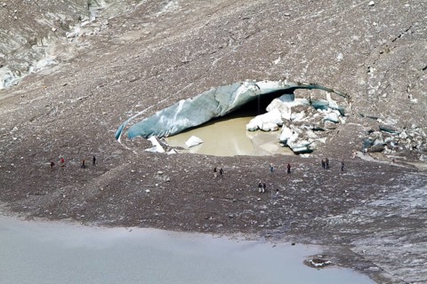 Hikers at the hole of collapsed ice in Pasterze Glacier