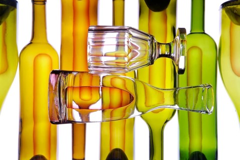 Carafe and wine glass in front of wine bottles