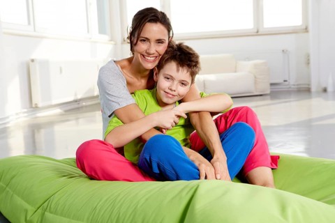 Mother and son in casual clothes sitting on a beanbag in a loft