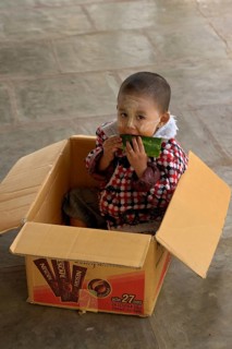 Young boy put in box to prevent him from running away while his mother is running her souvernir shop