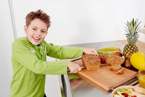 Boy cutting slices off a whole wheat bread