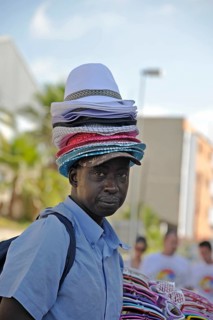Hat seller with a stack of hats on his head