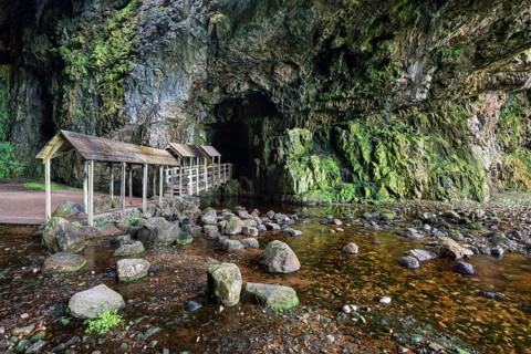 Covered bridge leading into the partly flooded with water Smoo Cave limestone cave