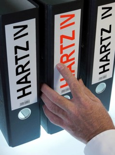 Hand reaching for a ring binder labeled Hartz IV