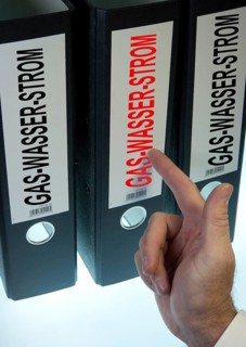 Hand pointing to a ring binder labeled Gas-Wasser-Strom
