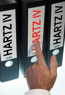 Hand pointing to a ring binder labeled Hartz IV
