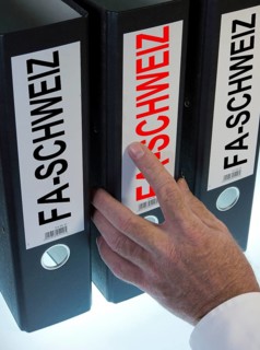 Hand reaching for file folders labeled 'FA-Schweiz'