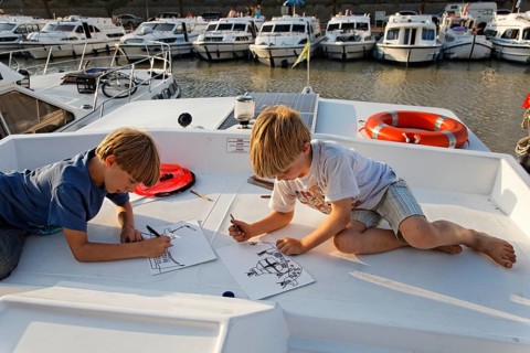 Two boys drawing on a houseboat in a harbour on the Canal du Midi