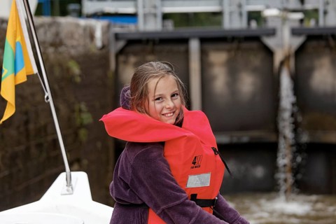 Girl wearing a life vest in a lock chamber of a rising lock