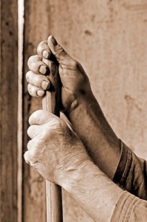 Hands marked by hard work supported on a pitchfork